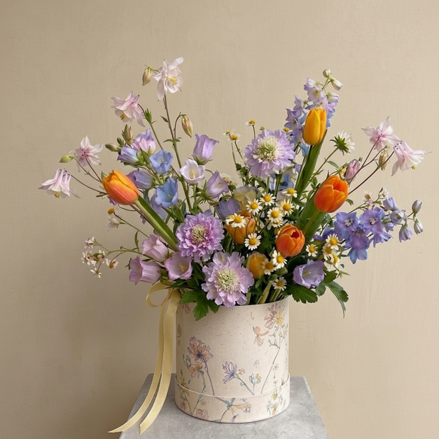Bouquet of colorful flowers in a decorative box on a neutral background